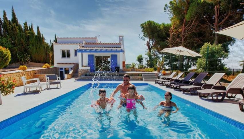 Happy family splashing in the private pool of Casa Azulino, a family-friendly vacation home in Lloret de Mar on the Costa Brava.